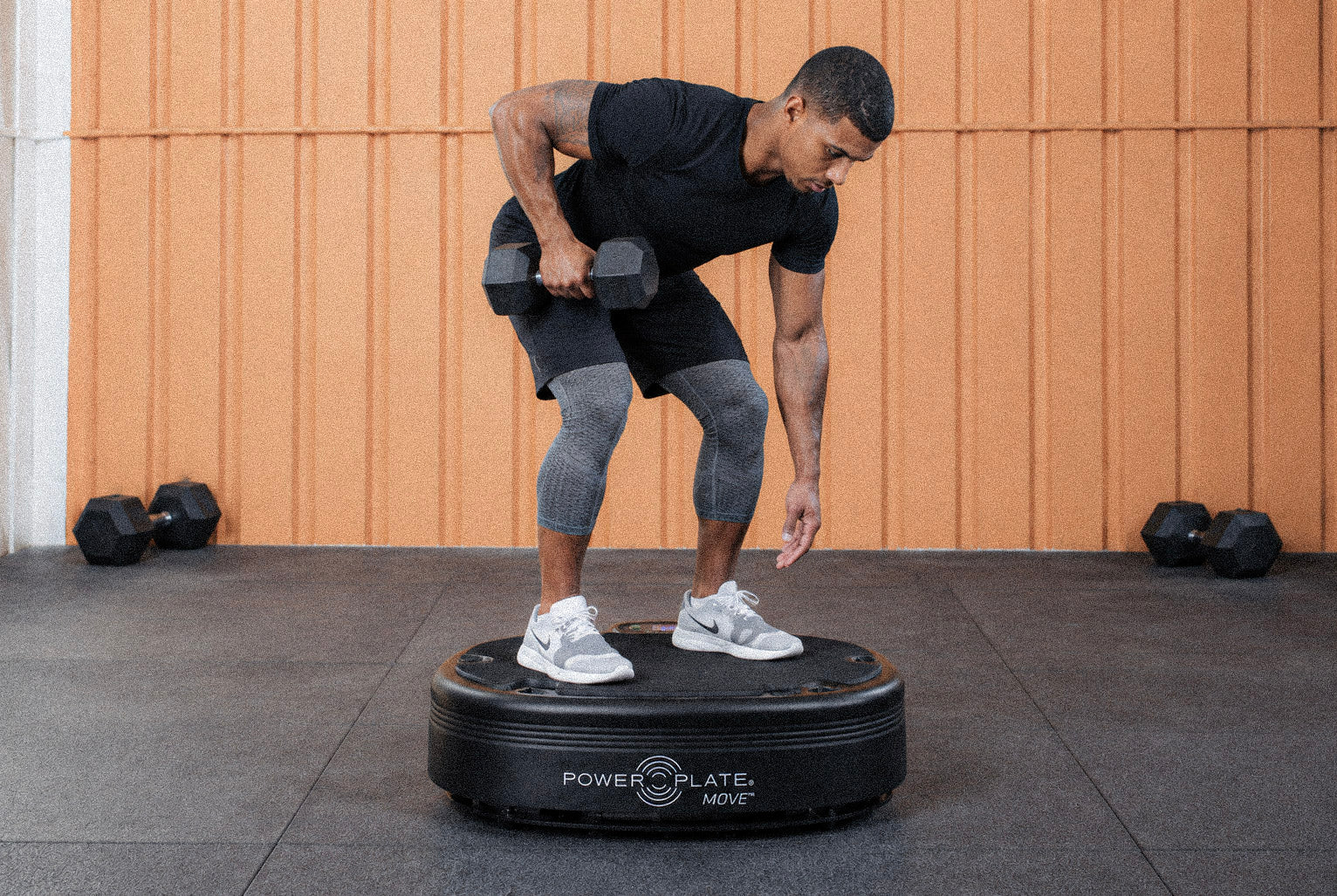 Man training with dumbbells on a Power Plate