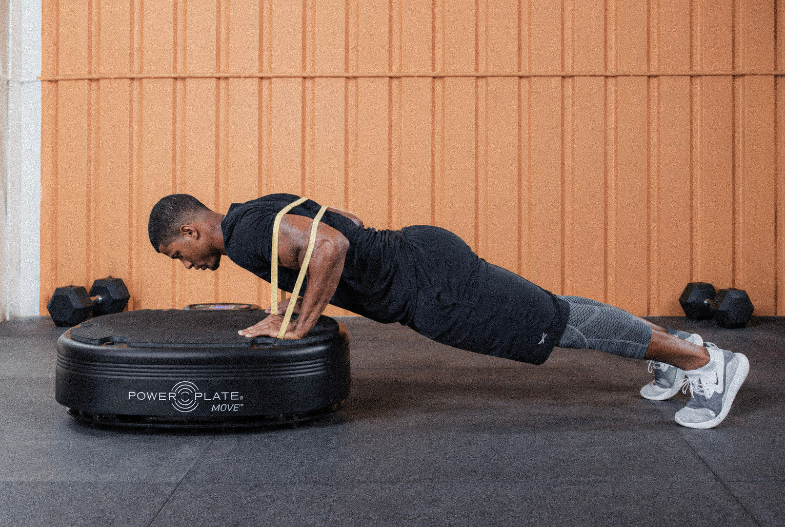 Man performing a resistance-band push-up on a Power Plate