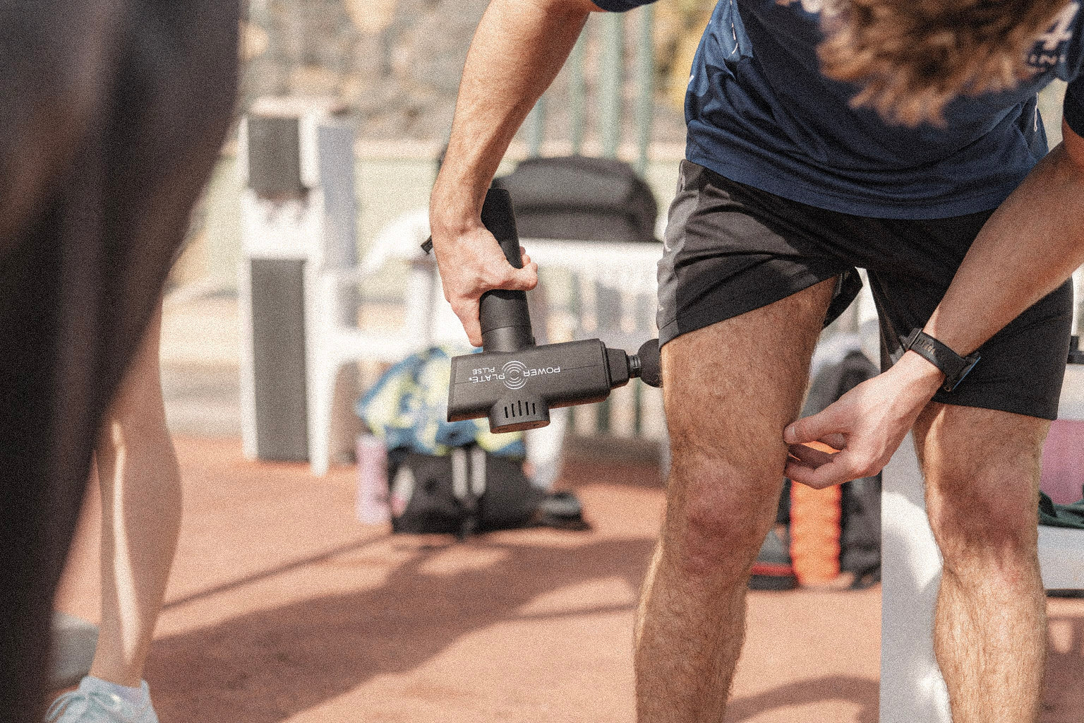 Man using a black Power Plate Pulse on his thigh.