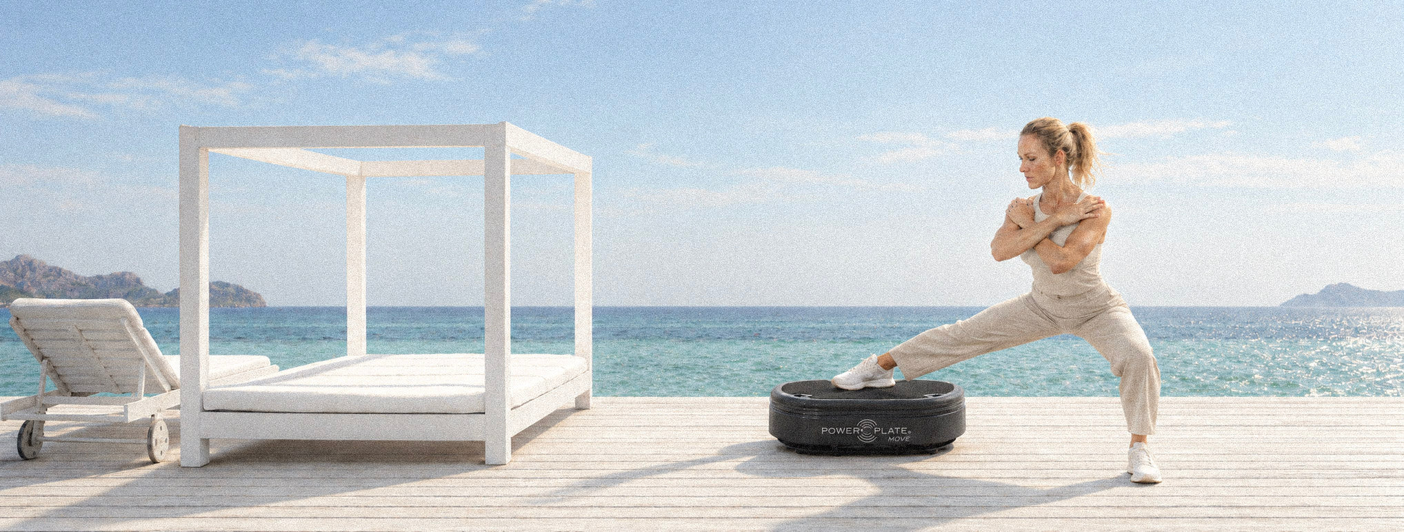 Woman exercising on a matte black Power Plate beside the sea.