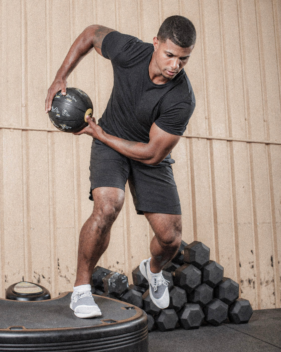 Man exercising with a medicine ball on a black Power Plate.