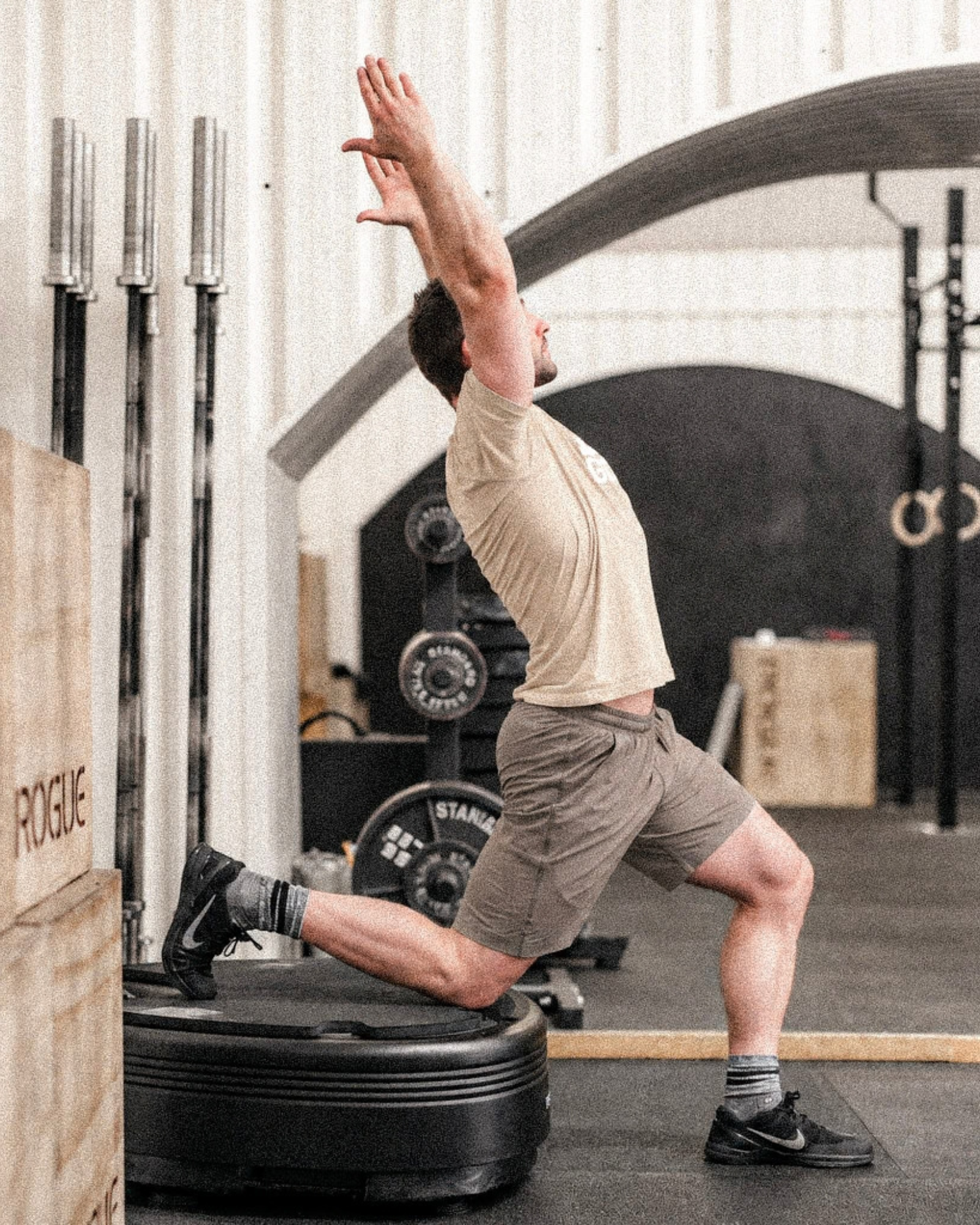 Man in beige clothing stretching on a black Power Plate.